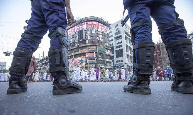 16일 방글라데시 경찰들이 시위를 벌이고 있는 정당 활동가들 옆에서 경계를 서고 있다. 다카=AFP연합뉴스