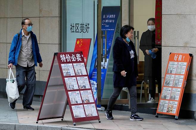 지난 5일 중국 베이징의 한 부동산 중개업소 앞을 시민들이 지나가고 있다. /AP 연합뉴스