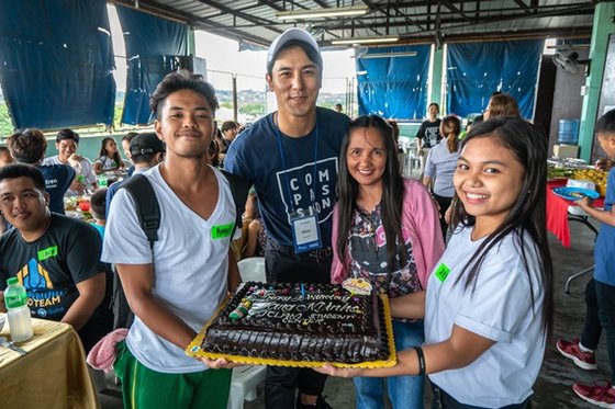 2018년, 필리핀의 한 어린이센터에서 가수 장민호 후원자가 생일 축하를 받고 있다. 한국 직원들도 전혀 몰랐을 정도로 깜짝 파티였다. 케이크 위에 생일 축하 메시지와 후원자의 이름 등이 적혀 있다.