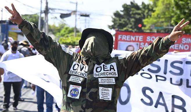 17일 엘살바도르 수도 산살바도르에서 군복을 입은 한 남성이 비트코인의 법정통화 채택 등 정부의 정책과 대법관 해임에 반대하는 시위에 참여하고 있다. 가슴에 'UN 권리', 'OEA(미주기구) 권리'라고 쓴 글씨를 붙이고 있다. AFP=연합뉴스