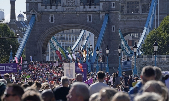 10월3일(현지시간) 영국 런던에서 열린 마라톤에 참여하는 선수들이 다리를 건너는 모습. 관중들이 마스크를 쓰지 않은 채 주변에서 구경하고 있다. 런던=AFP연합뉴스