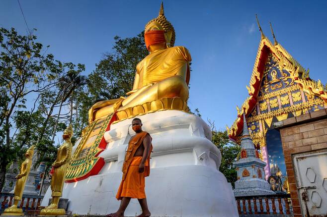 관광객 무격리 입국 준비하는 태국 - 태국 방콕 외곽의 한 불교 사원의 불상에 붉은 마스크가 씌어져 있다. 세계적인 관광대국인 태국은 11월 1일부터 코로나19 위험이 낮은 것으로 평가되는 미국, 싱가포르 등 5개국에 대해 무격리 관광 입국을 계획하고 있다고 11일 쁘라윳 찬오차 총리가 밝혔다. AFP 연합뉴스