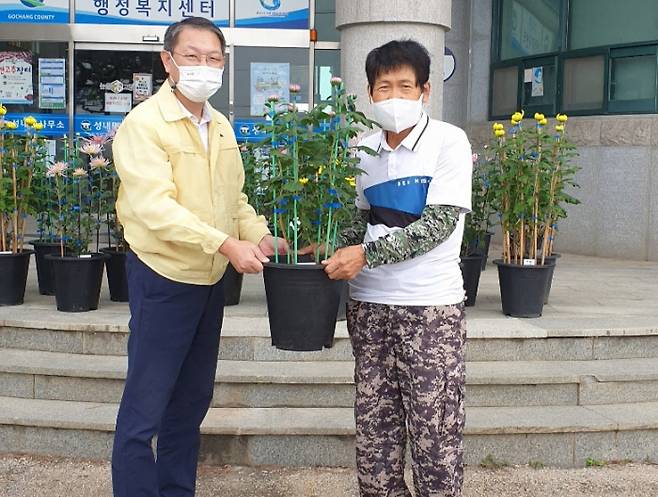 농민 김사배씨(오른쪽)가 40여개에 달하는 국화 화분을 성내면사무소 측에 전달하고 있다.    고창군 제공