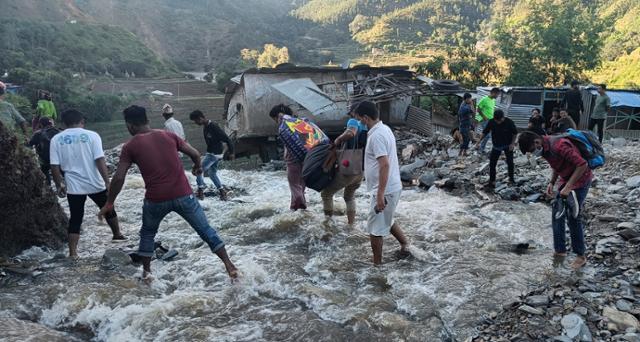 21일 네팔 서부 도시 디파얄 실가디에서 주민들이 물에 잠긴 길을 걸어서 건너가고 있다. AP 연합뉴스