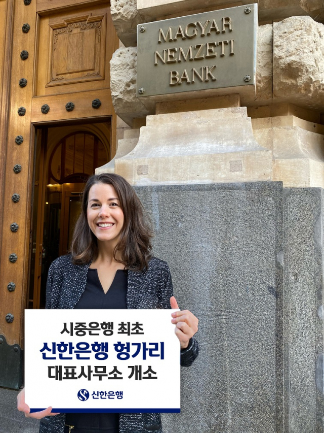 19일 신한은행이 헝가리 부다페스트 대표사무소의 한 직원이 개소를 축하하는 팻말을 들고 있다./사진 제공=신한은행