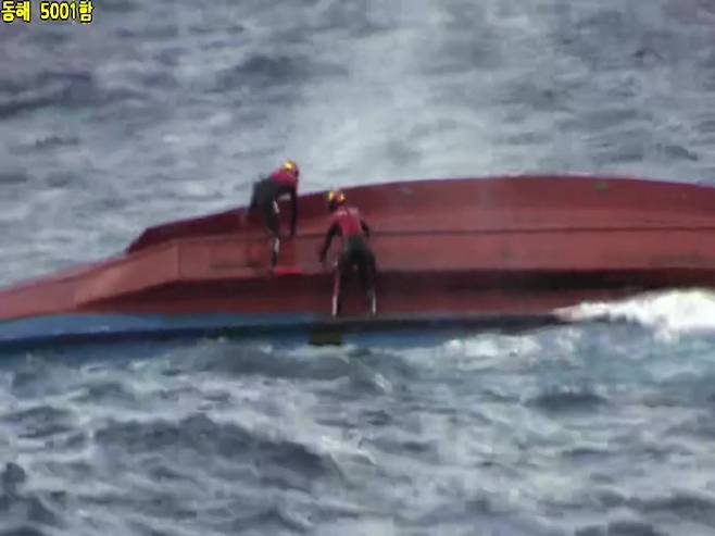해경 특수구조대원들이 지난 21일 오전 거친 파도가 몰아치는 가운데 독도 북동쪽 해상에서 전복된 어선에 진입을 시도하고 있다. 동해지방해양경찰청 제공