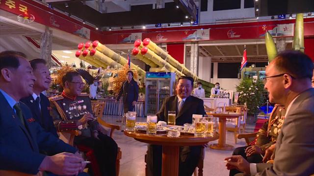 김정은 북한 국무위원장이 11일 평양 3대혁명전시관에서 열린 국방발전전람회 '자위-2021' 개막행사에 참석해 고위 간부들과 함께 생맥주를 마시며 흡족해 하고 있다. 평양=조선중앙TV 뉴시스