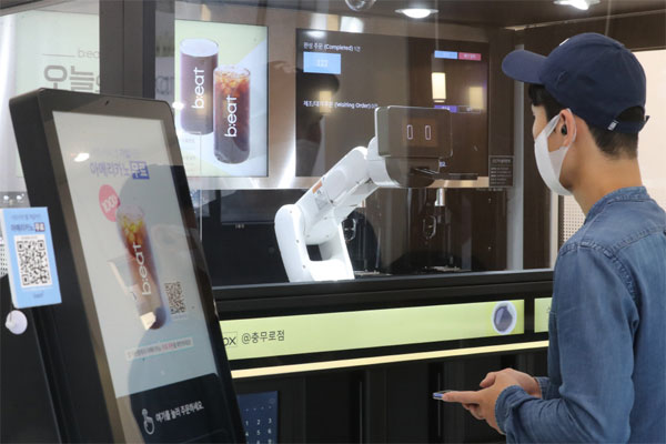 서울 중구에 위치한 24시간 무인 로봇 카페 `비트박스 충무로역점`에서 한 고객이 커피를 기다리며 바리스타봇을 바라보고 있다. 바리스타봇의 얼굴 액정에는 24가지 표정이 탑재돼 있으며, 몸체의 목과 허리를 움직여 커피를 만든다.  [박형기 기자]