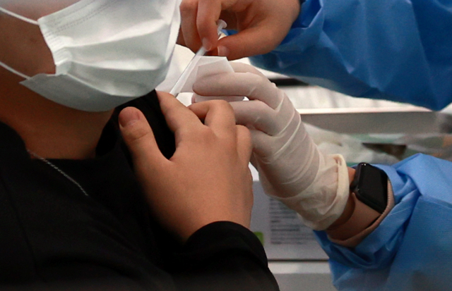 지난 23일 오전 서울 관악구민종합체육센터에 마련된 코로나19 백신 접종센터를 찾은 시민이 백신 접종을 받고 있다./연합뉴스