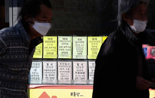 서울 서대문구의 부동산 중개업소에 게시된 매물 가격 안내판 앞을 시민들이 지나가고 있다./연합뉴스