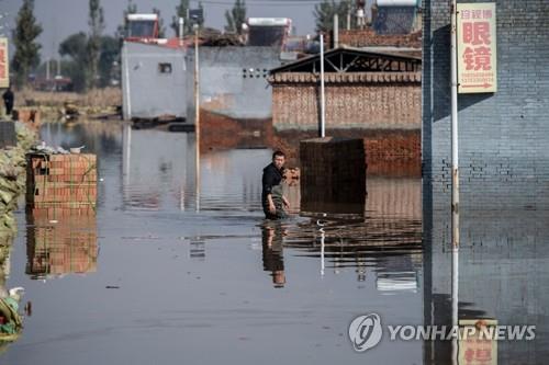 중국 산시성 홍수 피해 지역 걸어가는 주민     (진중 AFP=연합뉴스) 중국 북부 산시성 진중시의 홍수 피해 지역에서 지난 11일(현지시각) 한 남성이 물에 잠긴 거리를 걸어가고 있다. 최근 산시성에서 연일 내린 호우로 인해 176만 명 넘는 이재민이 발생했다고 글로벌타임스 등 중국 매체들이 보도했다. 2021.10.12. photo@yna.co.kr