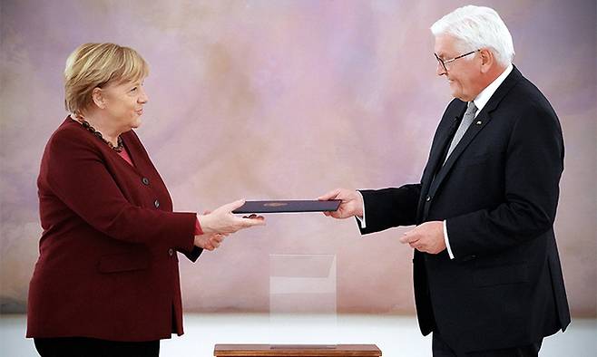 26일(현지시간) 독일 베를린 대통령관저에서 프랑크 발터 슈타인마이어 대통령(오른쪽)이 은퇴를 앞둔 앙겔라 메르켈 총리한테 퇴임 증서를 수여하고 있다. 메르켈은 독일 새 총리가 확정될 때까지만 임시로 총리직을 유지한다. 베를린=EPA연합뉴스