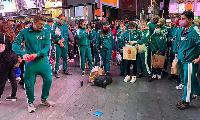 26일(현지시간) 미국 뉴욕 맨해튼 타임스스퀘어에서 ‘오징어 게임과 함께하는 뉴욕 속 한국여행’ 행사가 열려 시민들이 딱지치기를 하고 있다. 뉴욕=연합뉴스