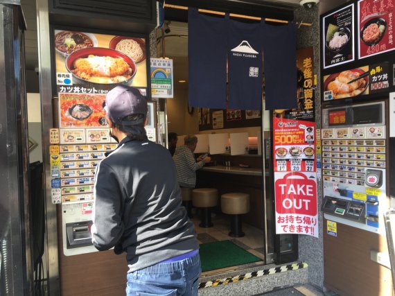 일본 도쿄 신바시 지역의 한 식당앞에서 한 남성이 메뉴 자판기에서 메뉴를 주문하고 있다. 사진=조은효 특파원