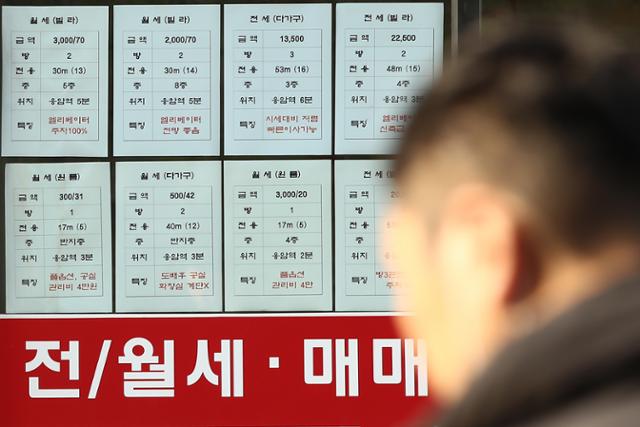 14일 서울의 한 부동산 업체 앞에 붙은 가격 공고를 지나가던 시민이 바라보고 있다. 연합뉴스