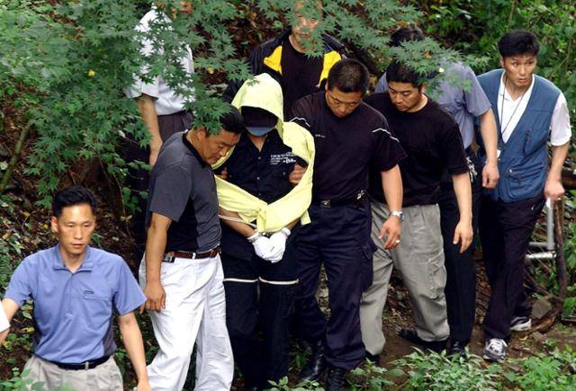 지난 2004년 7월 연쇄살인범 유영철이 체포된 뒤 현장 검증을 하기 위해 서울 서대문구 봉원사 계곡으로 내려가고 있다. 한국일보 자료사진