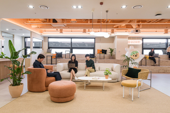 당근마켓 직원들이 지난 19일 서울 서초구 강남 교보타워에 있는 회사 사무실 로비에서 소파에 앉아 노트북을 보며 자유로운 분위기에서 회의를 하고 있다.  당근마켓 제공