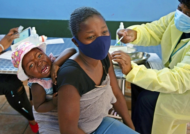 지난달 21일 남아프리카공화국 요하네스버그 인근에서 엄마 등에 업힌 아기가 백신 접종 중 칭얼거리고 있다. 조 파흘라 남아공 보건부 장관은 11월 25일 신종 ‘누 변이’ 바이러스가 발견됐다고 밝혔다./AP연합뉴스