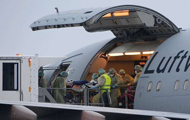 26일(현지시간) 독일 남부 바바리아주 메밍겐 공항에서 의료진들이 코로나19 감염 환자를 중환자실(ICU)로 옮기기 위해 군용기 에어버스 A310-900 MRTT로 옮기고 있다. [AFP 연합]