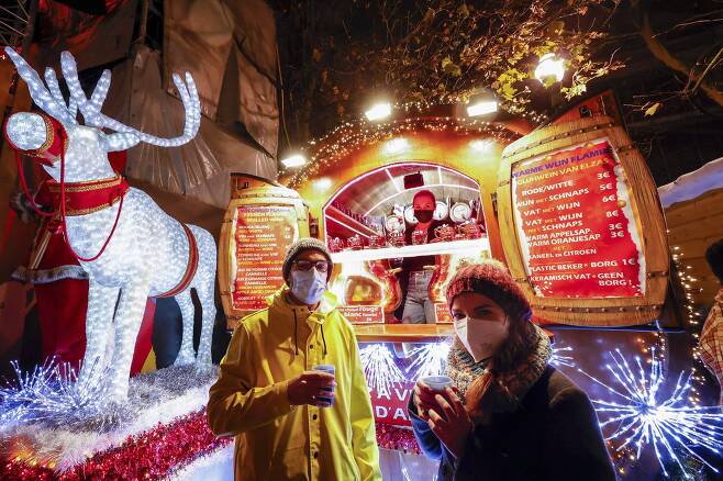 벨기에서도 오미크론 바이러스가 발견됐다. 27일 밤 벨기에 브뤼셀 시민들이 마스크를 착용한 채 크리스마스 장식을 한 부스에서 음료를 사서 마시고 있다. AP=연합뉴스