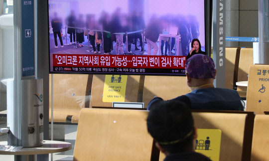 지난 1일 인천공항에서 방문객들이 코로나19 새 변이바이러스 '오미크론'과 관련된 뉴스를 보고 있다. 연합뉴스