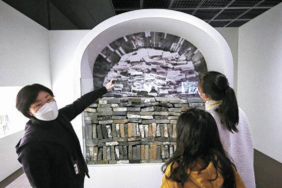 윤지연(왼쪽) 학예연구사가 총 614점이 나온 무령왕릉 입구 막음벽돌에 대해 설명하고 있다. 널문 바닥부터 수평과 수직으로 번갈아 쌓았으며, 위로 갈수록 쌓은 모습이 고르지 않다.