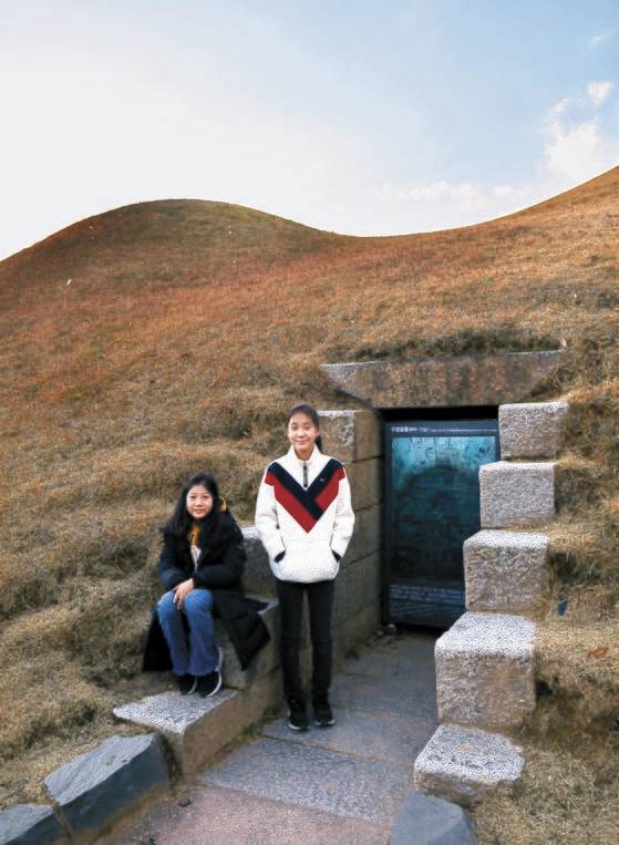 무령왕릉의 이모저모를 알아본 박하윤(왼쪽) 학생기자·원예진 학생모델이 실제 무령왕릉 앞에 섰다. 왕릉원 전시관에서는 모형 무령왕릉에 들어가 볼 수도 있다.