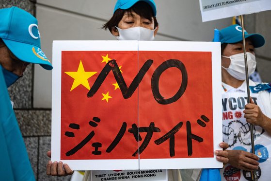 지난 10월 2일 일본 도쿄에서 '베이징 올림픽 보이콧'을 요구하는 시위대 중 한 명이 '노(NO) 제노사이드(대학살)'라고 쓴 종이를 들어보이고 있다. [AFP=연합뉴스]