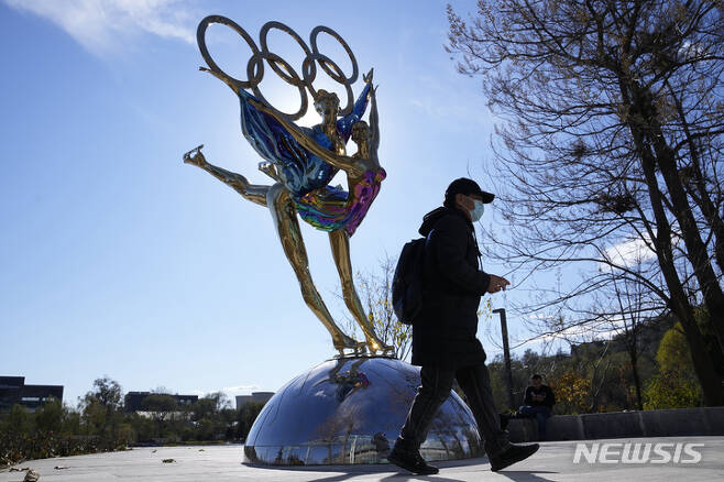[베이징=AP/뉴시스] 11월9일 중국 베이징 한 공원에 설치된 베이징 동계올림픽 기념 조형물 앞을 행인이 지나가고 있다. 2021.12.07