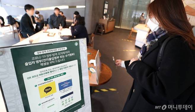 방역패스(접종증명·음성확인제)의 계도기간이 끝나고 의무화가 시작된 13일 서울 시내의 한 카페에서 한 시민이 QR코드 인증을 하고 있다. /사진=이기범 기자 leekb@