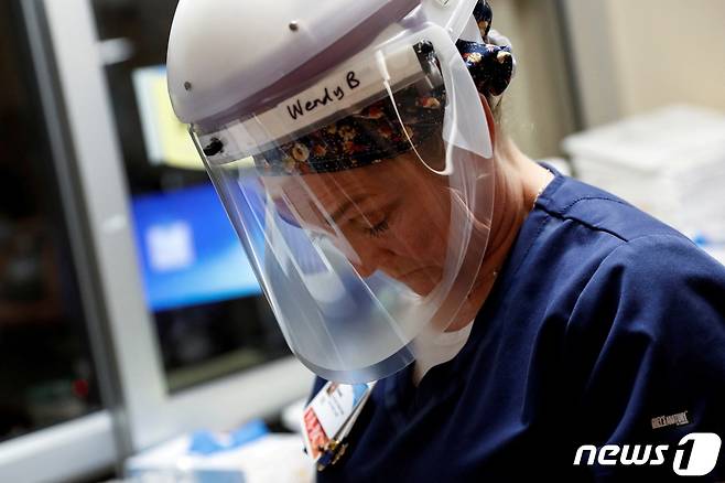 미국 플로리다 사라로타 메모리얼 종합병원 한 간호사가 중환자실 코로나 격리 병동에 들어가기 전 지친 얼굴로 바닥을 내려다 보고 있다. 2021. 9. 21. © 로이터=뉴스1 © News1 최서윤 기자
