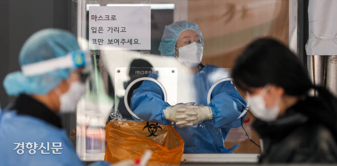 지난 12일 서울역 코로나19 임시 선별검사소에서 의료진이 손을 맞잡고 추위를 녹이고 있다. 이석우 기자