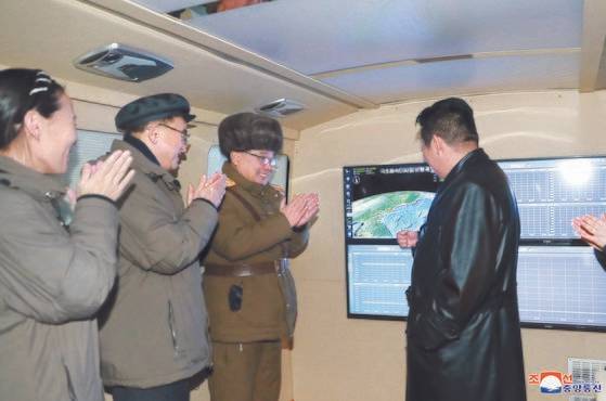 지난 11일 가죽코트를 입고 극초음속 미사일 시험발사 현장을 찾은 김정은 국무위원장(오른쪽). [연합뉴스]