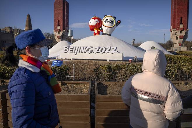 중국 수도 베이징에 설치된 동계올림픽 마스코트 조형물 앞으로 마스크를 쓴 시민들이 지나고 있다. AP연합뉴스