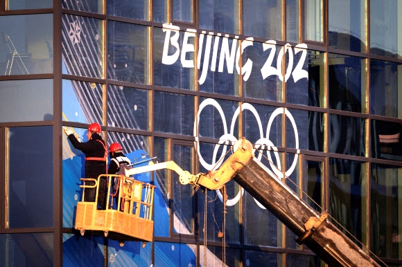 지난해 말 중국 베이징의 한 빌딩에서 노동자들이 빌딩 외벽에 ‘2022 베이징 동계올림픽’을 알리는 표지를 붙이고 있다. 베이징 로이터 연합뉴스
