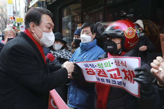 지난 2일 서울 종로구의 한 음식점에서 윤석열 후보가 코로나19 피해 자영업자들과 간담회를 마친 뒤 네트워크본부가 적힌 피켓을 든 지지자와 인사하고 있다.