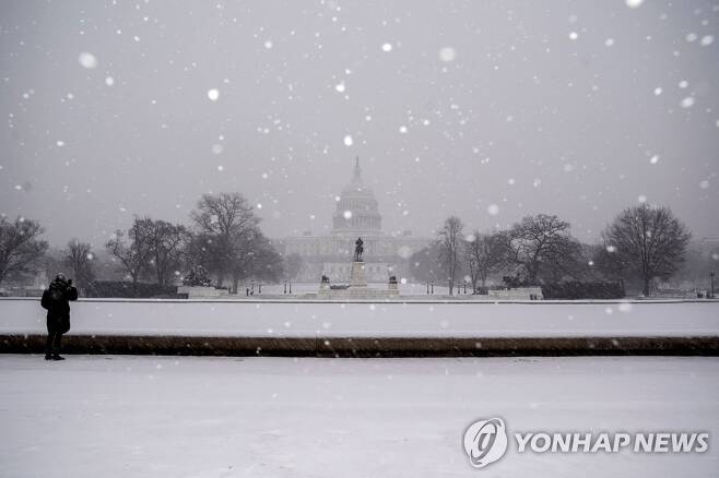 눈내리는 워싱턴DC (워싱턴DC AFP=연합뉴스) 16일(현지시간) 눈이 내리는 미국 워싱턴DC에서 의사당 사진을 찍고 있는 한 시민. 2022.1.17