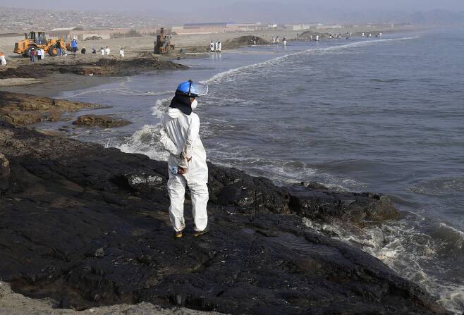 페루의 한 방제요원이 17일 검은 기름으로 덮인 카야오 지방 벤타니야의 카베로 해안에 서 있다. AP=연합뉴스
