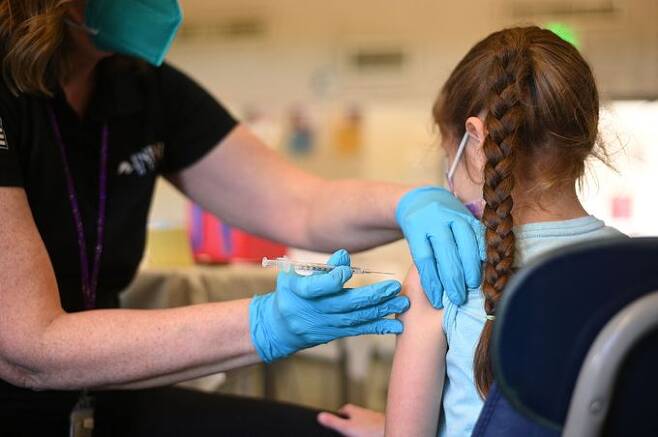 19일(현지시간) 미국 캘리포니아주 로스앤젤레스(LA)의 코로나19 백신 접종소에서 한 여자아이가 백신을 맞고 있다. LA=AFP연합뉴스