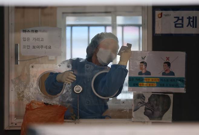 이달 6일 오전 서울역 코로나19 임시 선별검사소에서 의료진이 유리벽에 붙은 얼음 조각을 긁어내고 있다. 연합뉴스 제공