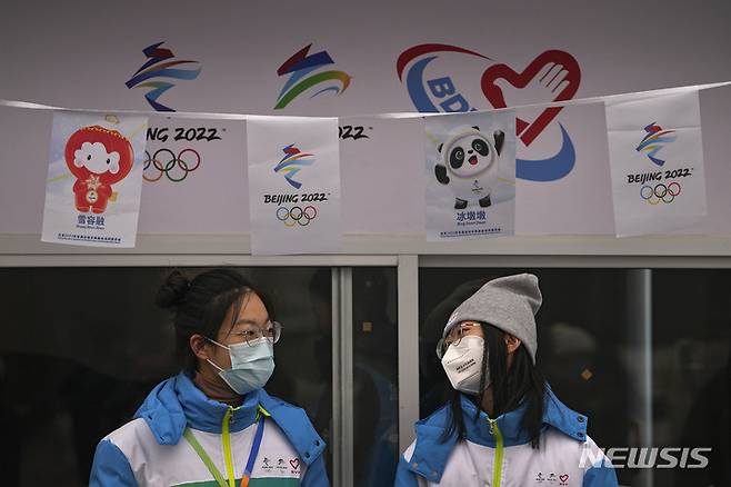 [베이징=AP/뉴시스] 23일 중국 베이징 도심의 한 동계올림픽 안내부스에서 마스크를 쓴 자원봉사자들이 담소를 나누고 있다. 2022.01.23