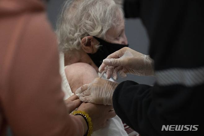 [네타니아=AP/뉴시스] 5일(현지시간) 이스라엘 네타니아의 한 사설 요양원에서 한 할머니가 화이자 백신 4차 접종을 하고 있다. 이스라엘 정부는 전염력이 강한 오미크론 변이로 신규 감염자 수가 사상 최대를 기록했다고 밝혔다. 2022.01.06.
