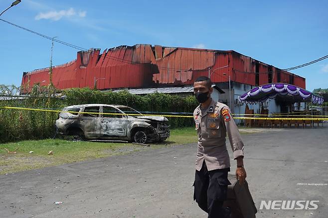 [소롱=AP/뉴시스] 25일(현지시간) 인도네시아 서파푸아주 소롱의 한 나이트클럽에서 화재가 발생한 후 한 경찰관이 현장 근처에서 근무하고 있다. 경찰은 나이트클럽 내에서 패싸움이 일어난 후 화재가 발생했다며 총 19명이 숨졌다고 밝혔다. 2022.01.25.