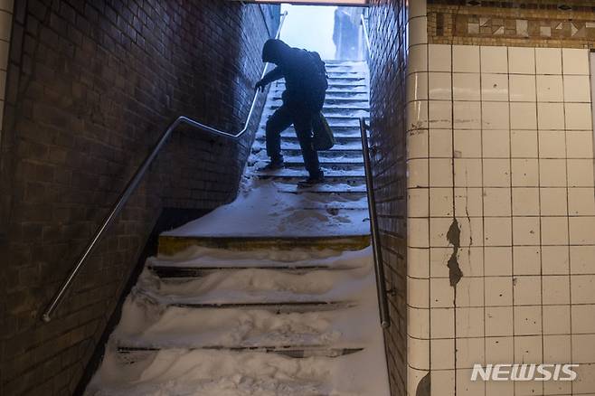 [뉴욕=AP/뉴시스]뉴욕 브루클린에서 29일(현지시간) 한 남성이 눈 덮인 지하철 계단을 조심스럽게 걸어 내려가고 있다. 허리케인급의  돌풍을 동반한 폭풍이 29일(현지시간) 미 동북부 지역을 강타해 45㎝가 넘는 폭설이 쏟아지고, 해안가에 홍수가 발생했으며 광범위한 정전이 발생할 수 있다고 예보됐다. 기상 예보관들은 상황이 더 악화되고 매서운 추위가 뒤따를 것이라고 경고했다. 2022.1.30
