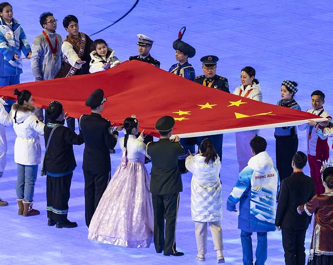 4일 오후 중국 베이징 국립경기장에서 열린 2022 베이징 동계올림픽 개회식에서 치마 저고리와 댕기 머리를 등 한복 복장을 한 공연자가 개최국 국기 게양을 위해 중국의 오성홍기를 옮기고 있다. [연합]