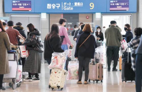 지난해 에어서울이 진행한 해외 무착륙 비행의 승객들이 면세품을 들고 탑승구로 향하고 있다. 뉴시스