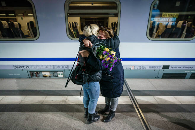 우크라이나 국기색 꽃을 든 한 시민이(오른쪽) 2일 우크라이나 피란민을 태운 열차에서 내린 승객을 끌어안고 있다. / EPA연합뉴스
