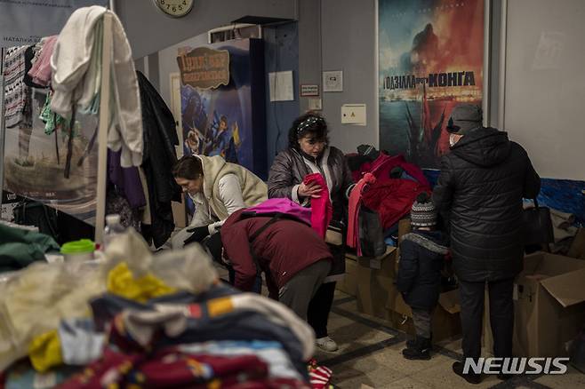 [르비우=AP/뉴시스] 12일(현지시간) 우크라이나 르비우에서 구호소로 사용되는 극장 안에서 시민들이 옷가지를 고르고 있다. 3주째 접어든 러시아의 공격으로 250만 명 이상의 우크라이나인이 피난한 것으로 나타났다.  2022.03.13.