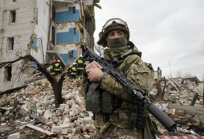 한 우크라이나 군인이 러시아군의 공습으로 파괴된 수도 키이우 외곽의 한 아파트 앞에 서 있다. AP연합뉴스