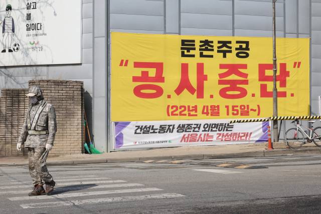 지난 11일 서울 강동구 둔촌동 ‘둔촌주공아파트 재건축 사업’(올림픽파크포레온) 공사 현장에 공사 중단을 예고하는 현수막이 붙어 있다. 연합뉴스